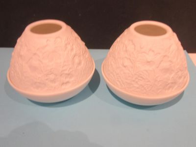 two white vases sitting on a blue table