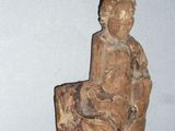 une petite statue représentant une personne assise sur un tabouret
