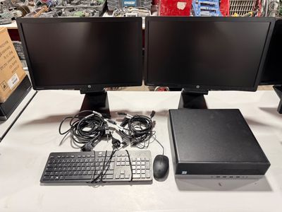two computer monitors and a keyboard on a table