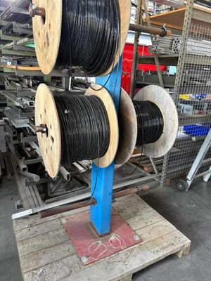 deux bobines de fils noirs et blancs posées sur une palette dans un entrepôt