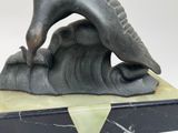 statue of a man riding a wave on top of a black and white marble base