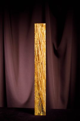 a tall glass vase with a long stem of grass in it