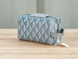 a grey and white toilet bag sitting on top of a wooden table