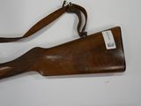 a wooden rifle with a leather sling on a white surface