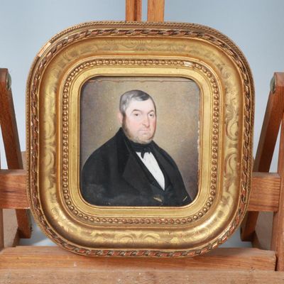 portrait d'un homme en costume noir et nœud papillon, dans un cadre doré