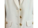 a white suit with gold buttons and a blue tie