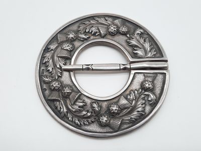 une broche ancienne en argent ornée de fleurs et d'un couteau au centre