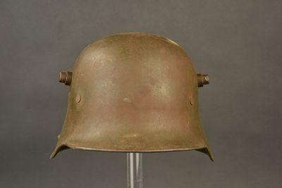 an old helmet on a metal stand on a gray background