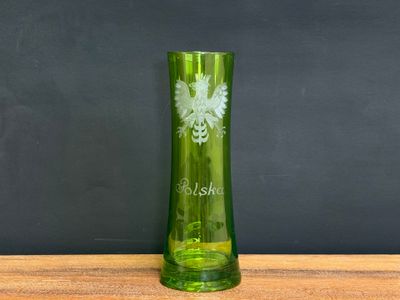 a green glass vase sitting on a wooden table