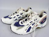 une paire de baskets blanches et bleues posées sur une surface blanche, avec un verre de vin en arrière-plan