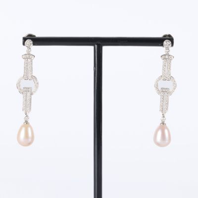pair of pearl and diamond earrings on a black stand