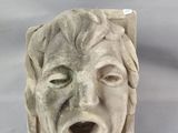 une sculpture en pierre représentant le visage d'un homme, la bouche ouverte