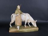 une figurine représentant une femme assise sur une vache
