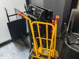 un diable jaune qui se trouve à côté d'une poubelle noire