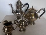 trois théières en argent et un pichet posés sur une table