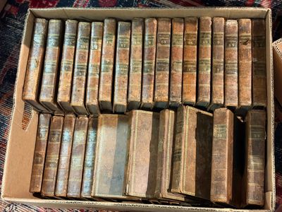 une boîte remplie de vieux livres posée sur un tapis