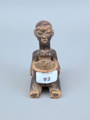 une vieille figurine représentant un homme tenant un bol de nourriture