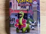 Jeu de cartes à collectionner Pokémon dans une boîte en métal posée sur une table en bois