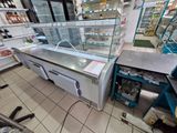 a display case in the middle of a store filled with food