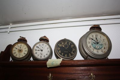 many different clocks on a shelf in a room