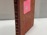 un vieux livre sur lequel est collé un autocollant rose, posé sur une table