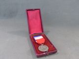 une boîte rouge contenant une médaille, posée sur une table