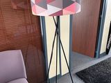 a lamp that is on a tripod next to a chair