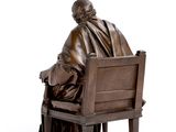 a bronze statue of a man sitting on a bench