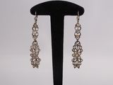 a pair of silver earrings on a black stand with a white background
