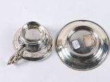 a silver tea cup and saucer on a white table