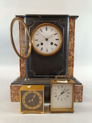 une horloge posée sur une table, à côté de deux petites horloges