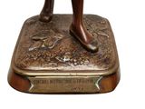 bronze statue of a woman holding a tennis racquet on top of a plaque