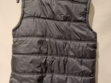 the back of a gray vest hanging on a white wall