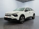Une voiture blanche est garée dans une pièce blanche au sol noir.