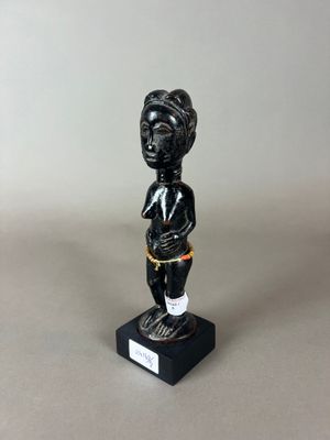 une figurine noire représentant une femme avec un panier sur la tête