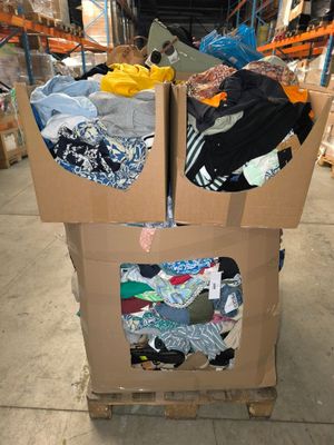deux cartons sur lesquels sont posés des vêtements, dans un entrepôt