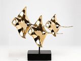 brass sculpture of three fish on a black base on a white background