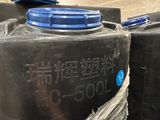 a person that is holding a plastic container in front of some water tanks