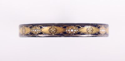 un gros plan d'un bracelet doré et noir sur fond blanc