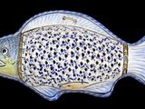 a blue and white fish shaped dish on a black background