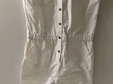 an image of a white jumpsuit with buttons and lace on it