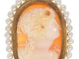 un gros plan sur un pendentif en camée d'or et de perles représentant le visage d'une femme