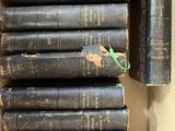Plusieurs vieux livres sont empilés dans une boîte en carton posée sur une table