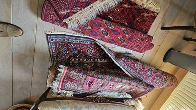 Plusieurs tapis orientaux sont disposés sur un parquet.