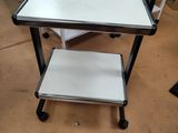 une table blanche avec un plateau noir et une étagère blanche posée dessus