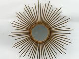 a gold sunburst mirror on a white wall