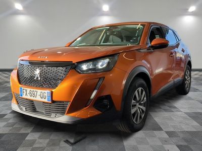 La voiture orange est garée dans le showroom, sur le sol à damier.