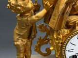 a gold clock with a statue of an angel and a child