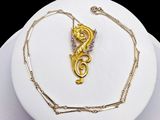 a gold necklace with a dragon on it on a white plate