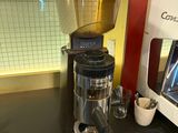 a coffee grinder sitting on a counter next to a cup of coffee